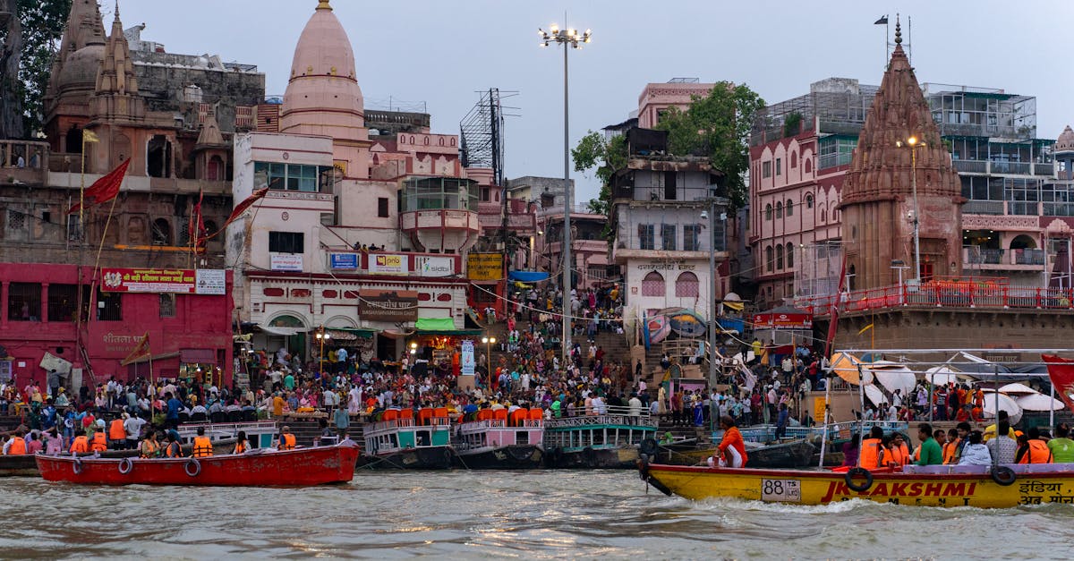Bustling riverfront scene in Varanasi with boats and traditional architecture.