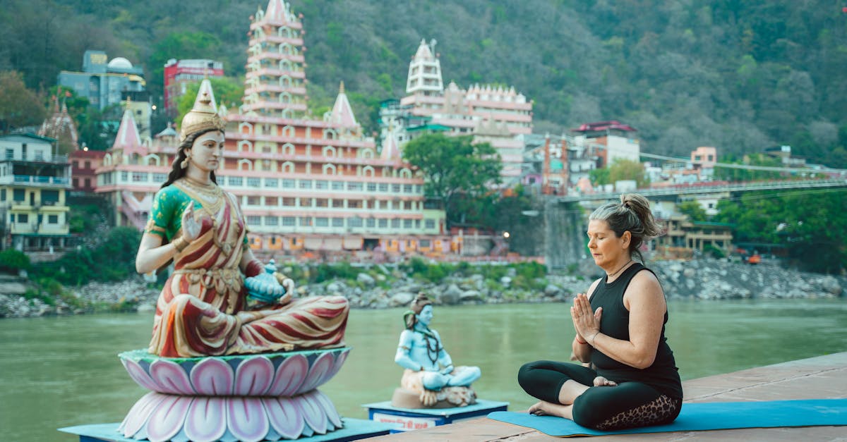 Woman meditating beside a statue by the Ganges in Rishikesh, capturing spirituality and serenity.