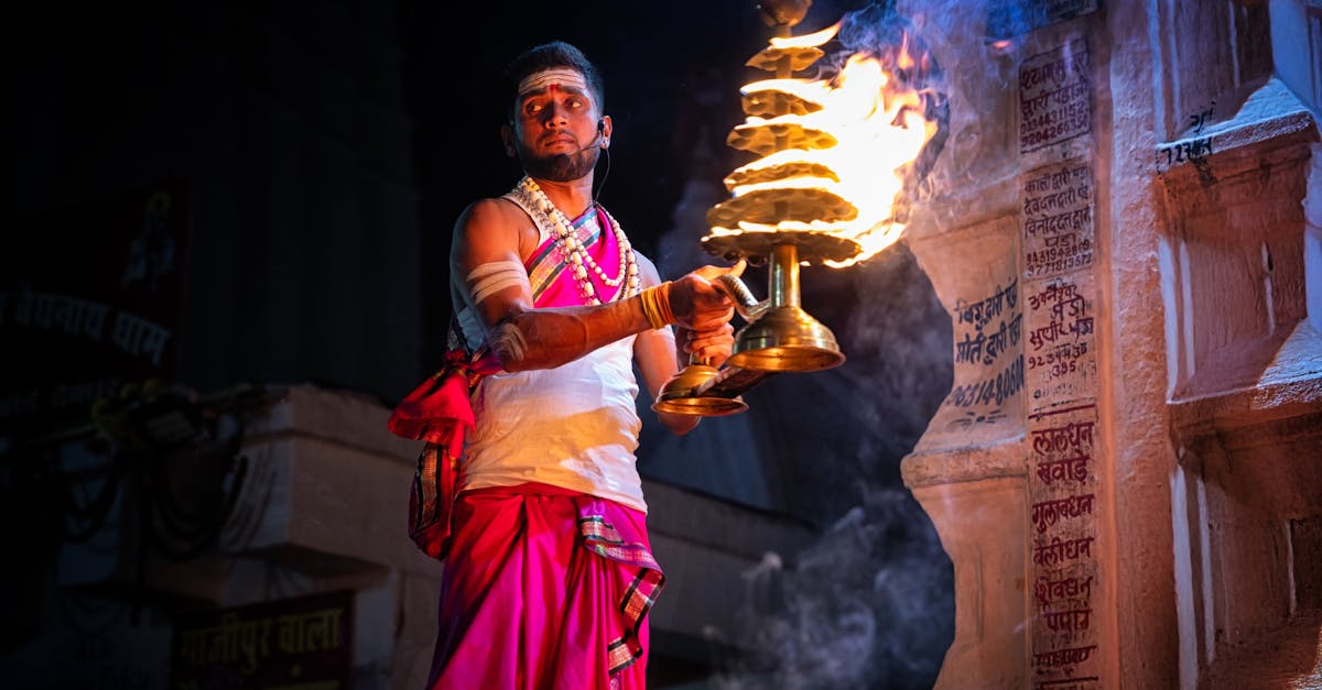 Hindu priest in Deoghar, India performing ritual with fire at night, showcasing traditional attire and ceremonial practice.